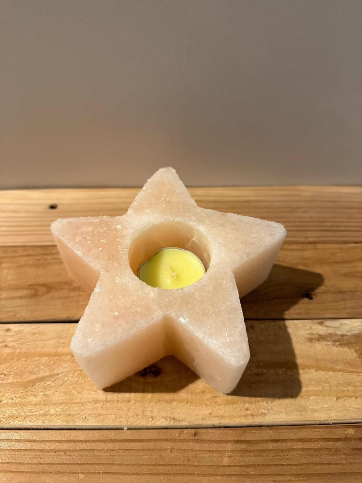 Handgemaakte stervormige waxinelichthouder van natuurlijke zoutsteen met warm oranje gloed