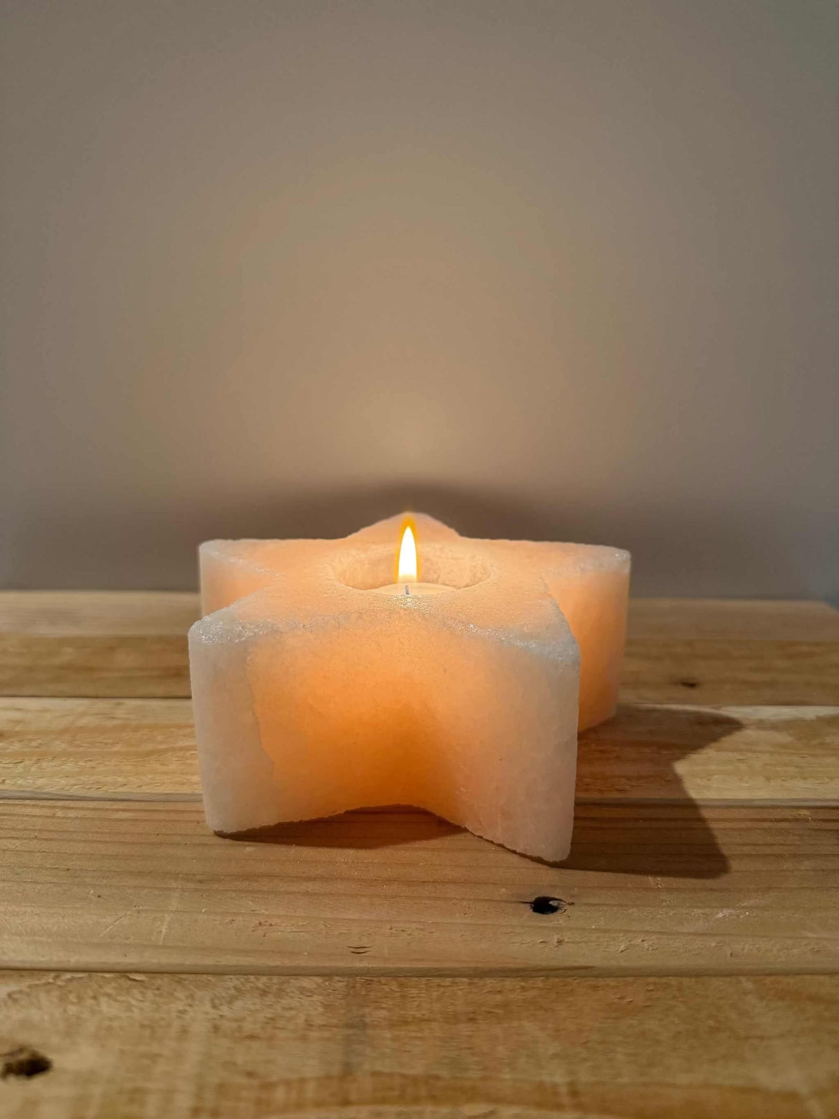 Handgemaakte stervormige waxinelichthouder van natuurlijke zoutsteen met warm gloeiend licht