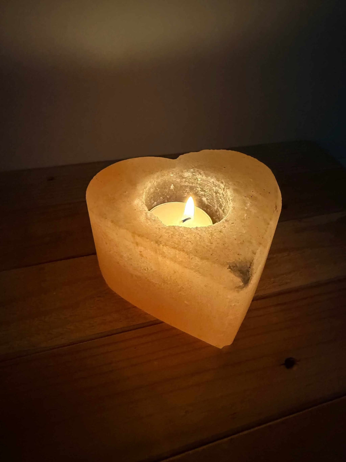 Handgemaakte hartvormige waxinelichthouder van natuurlijke zoutsteen met warm oranje gloed