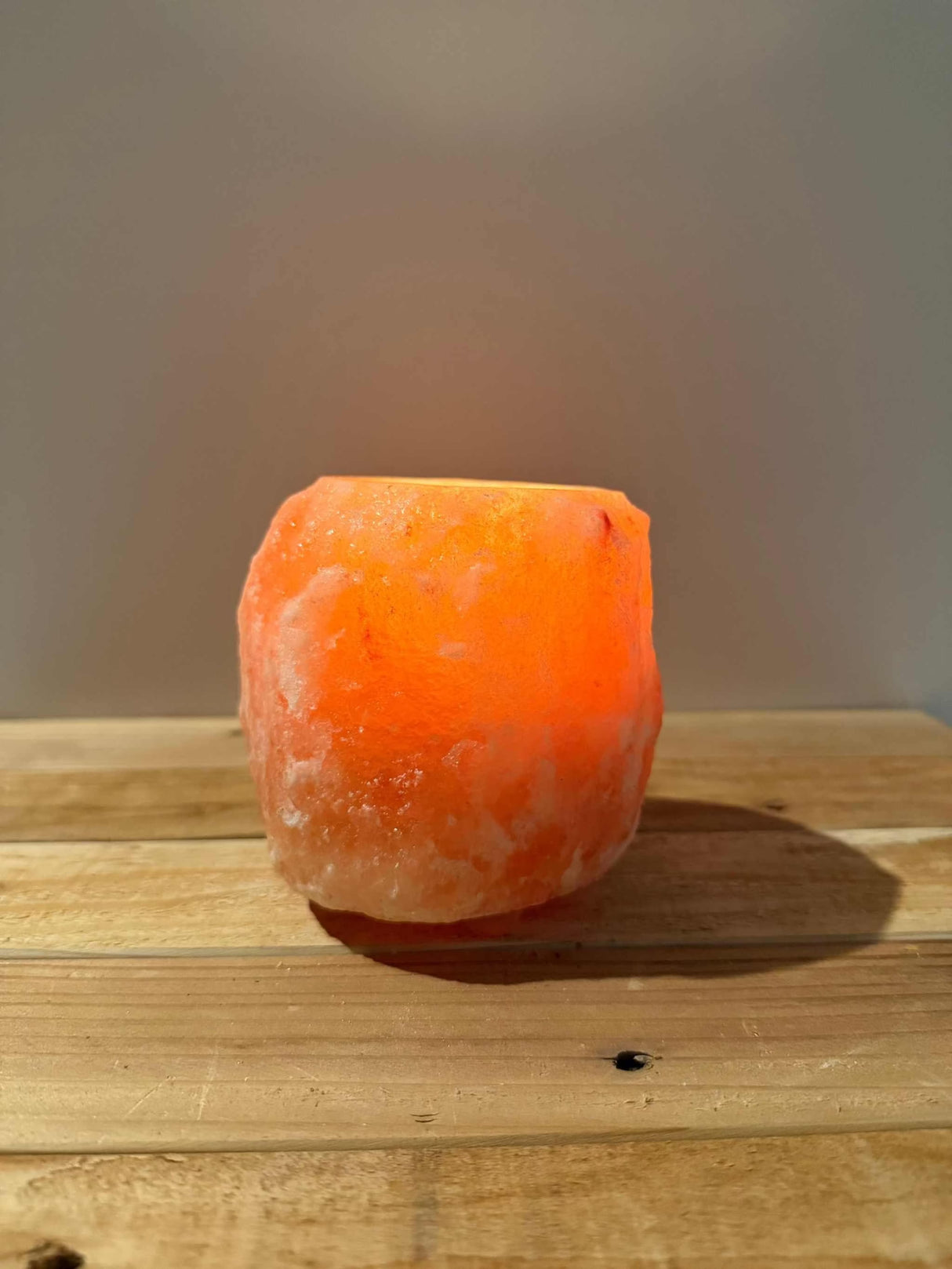 Handgemaakte rode natuurlijke zoutsteen waxinelichthouder met siliconen voetjes en warme gloed.