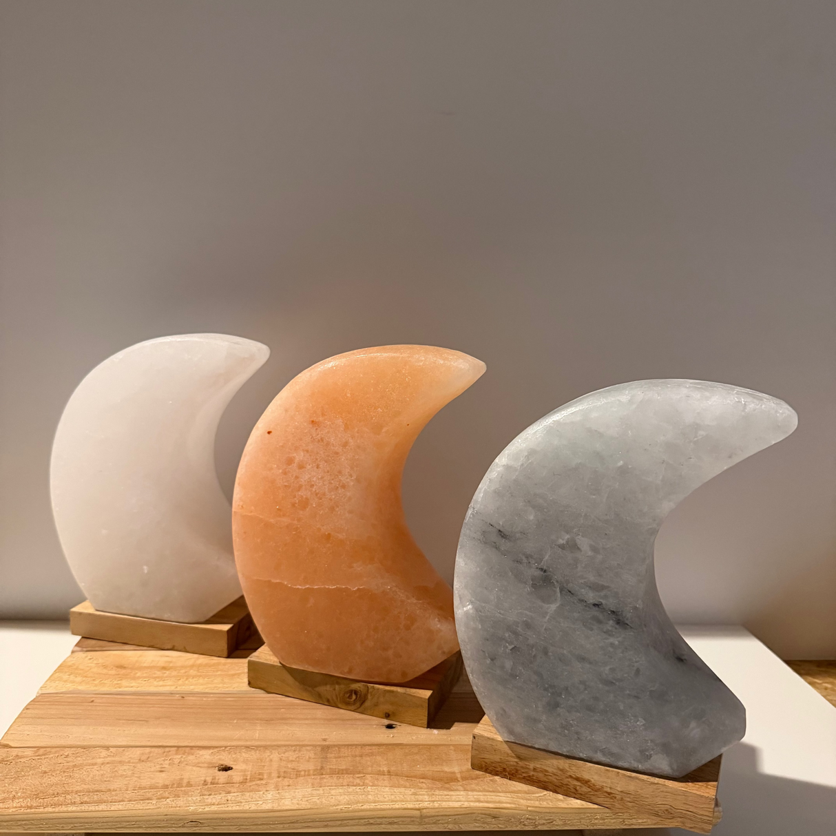 Handgemaakte maanvormige Himalaya zoutlamp in roze, grijs of wit met warme gloed en rustgevende sfeervolle uitstraling.