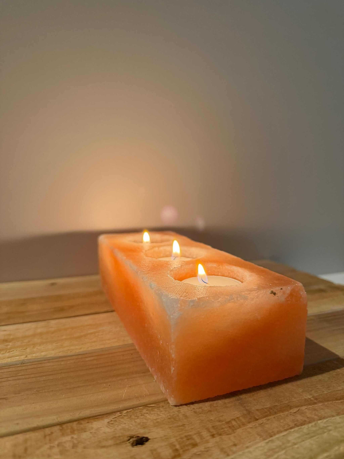 Schuin zijaanzicht Himalaya zoutsteen waxinelichthouder rechthoek met brandende waxinelichtjes