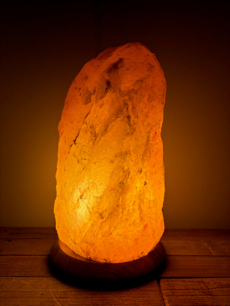 Grote Himalaya zoutlamp 10-12kg op houten voet, sfeerlicht en luchtzuivering voor woonkamers.