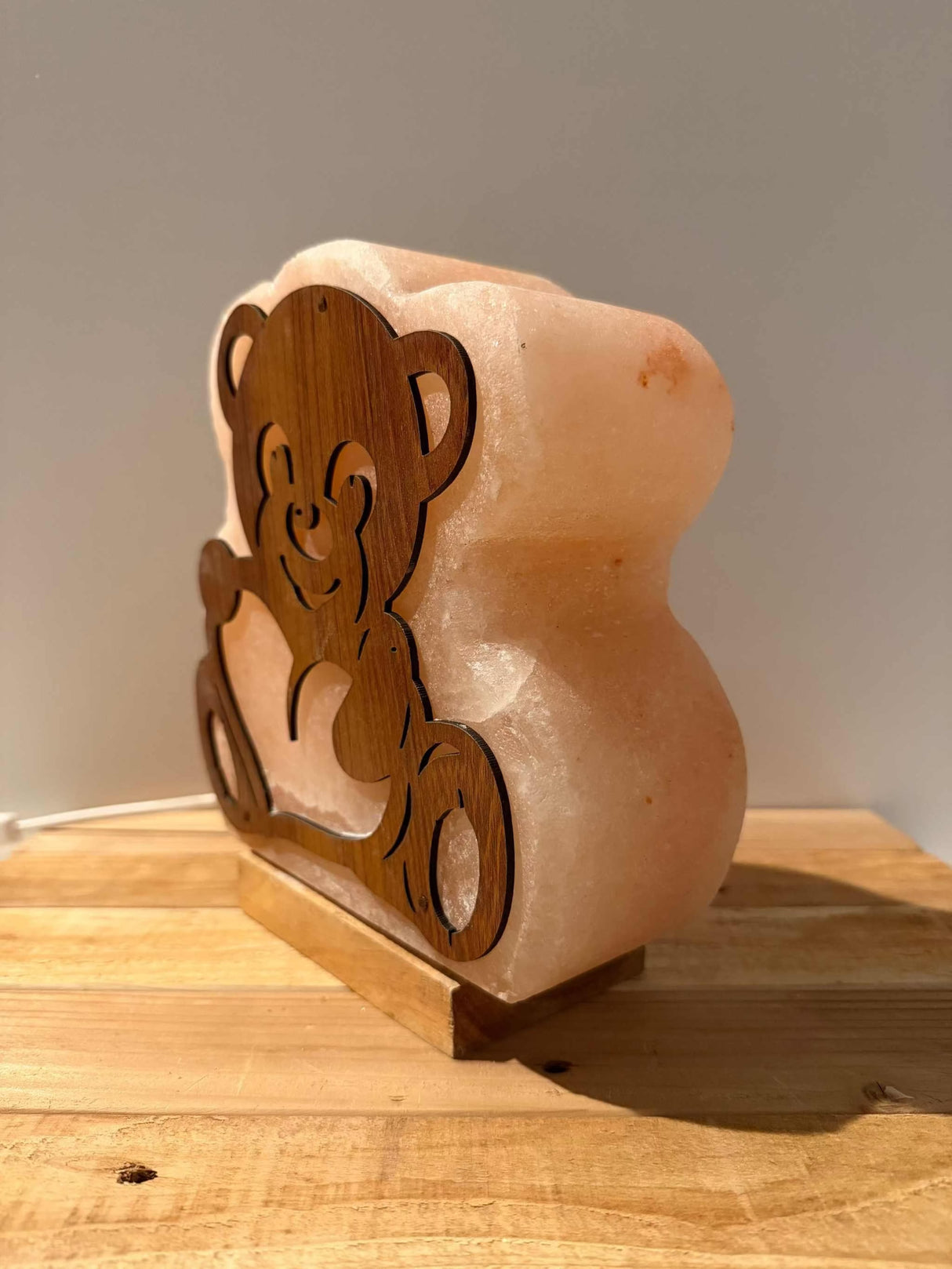 Handgemaakte Himalaya zoutlamp in de vorm van een beer met warm licht en houten voet.