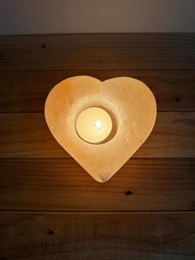Handgemaakte hartvormige waxinelichthouder van natuurlijke zoutsteen met warm oranje gloed
