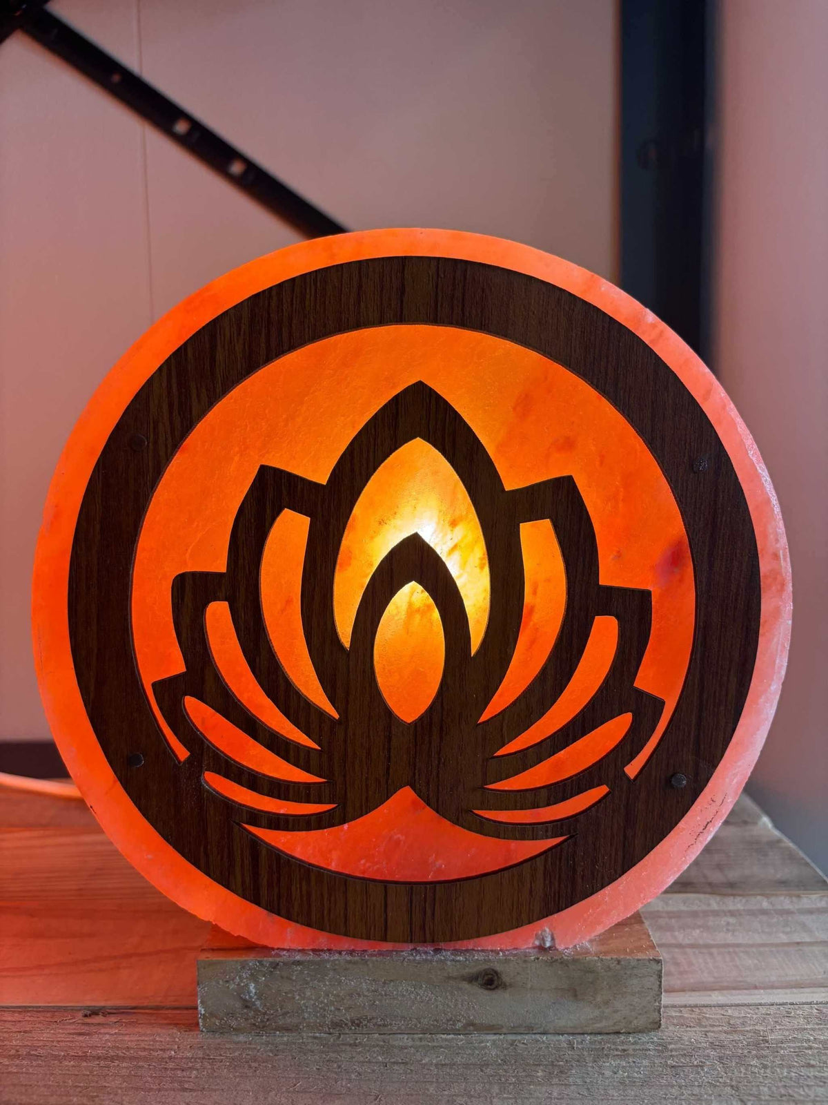Handgemaakte Himalaya zoutlamp met 3D bloemmotief en warme oranje gloed op houten voet