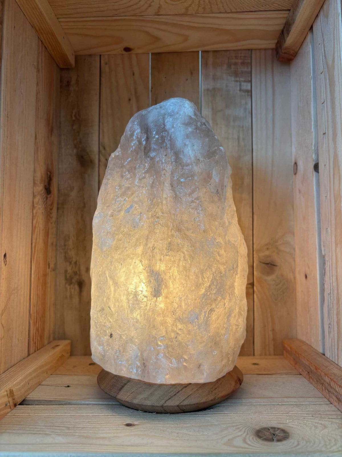 Brandende grijze Himalaya zoutlamp 4-6 kg op houten voet in een houten kist