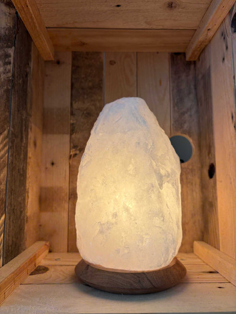 Brandende witte Himalaya zoutlamp 4-6 kg op houten voet in een houten kist