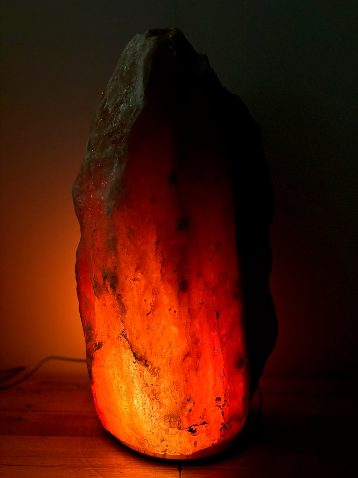 Donkere Himalaya zoutlamp 50–60 kg met diepe gloed op stevige houten voet