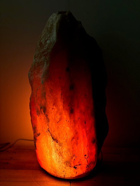 Donkere Himalaya zoutlamp 50–60 kg met diepe gloed op stevige houten voet