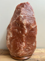 Donkere Himalaya zoutlamp 60–70 kg in natuurlijke diepe tinten op stevige houten voet